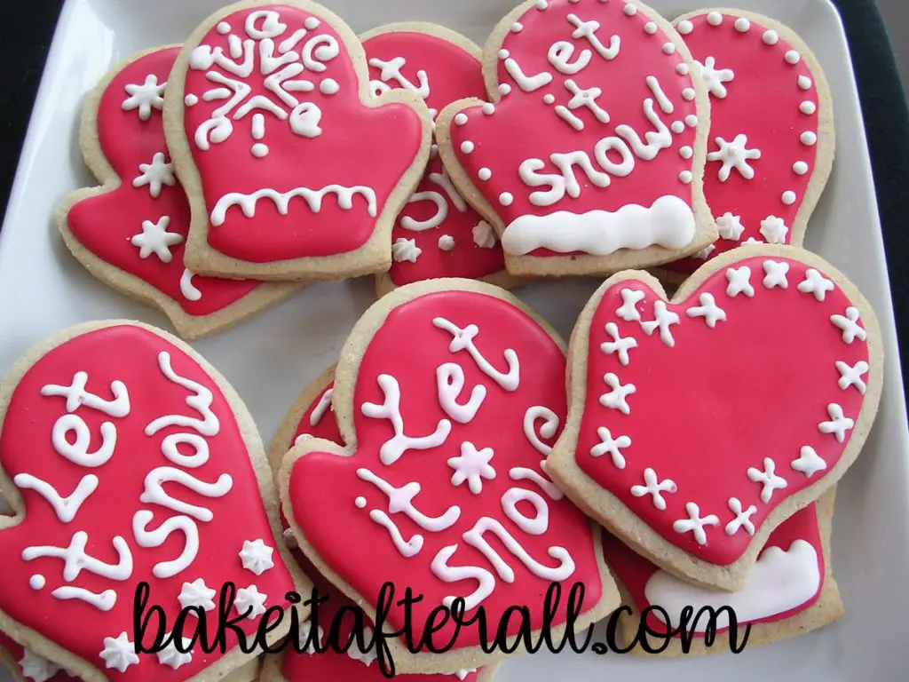 Brown Sugar and Spice Winter Mitten Cookies on a white platter decorated with "Let it snow!" sayings and winter designs