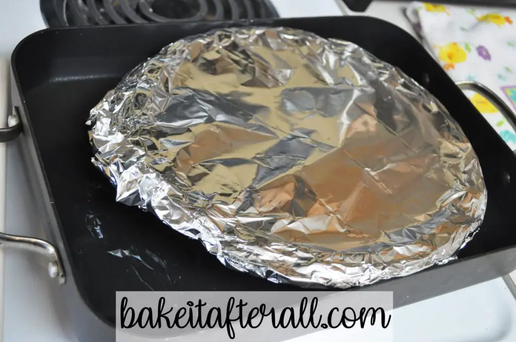 roasting pan with foil covered pie plate inside
