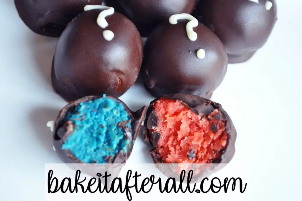 Two Oreo truffles with bites taken out of them - one with blue inside and one with pink inside