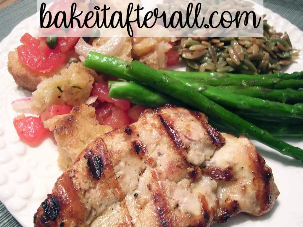 panzanella tomato bread salad on a plate with parmesan basil orzo, Italian dressing marinated chicken breast, and grilled asparagus