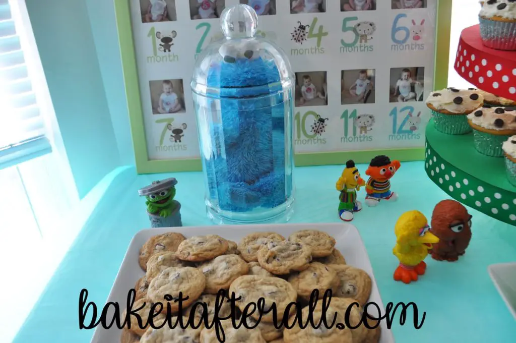 Cookie Monster trapped in jar behind plate of chocolate chip cookies