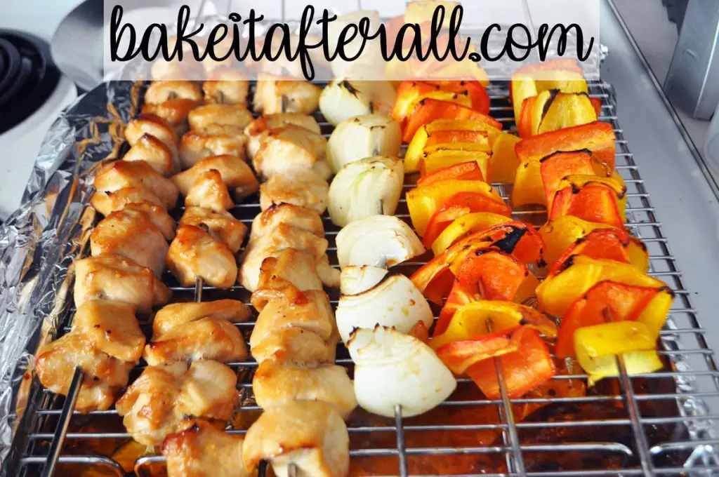 cooked honey chicken kabobs, onion, and bell pepper kabobs on a baking rack