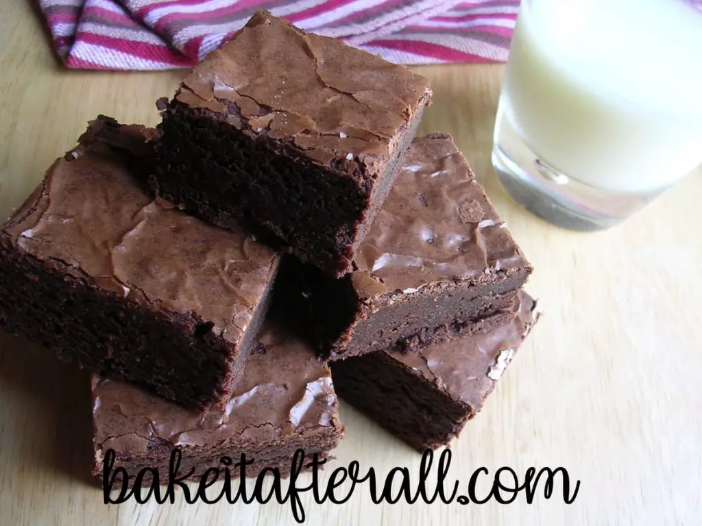 Chewy Fudgy Brownies on a wooden table with a glass of milk 