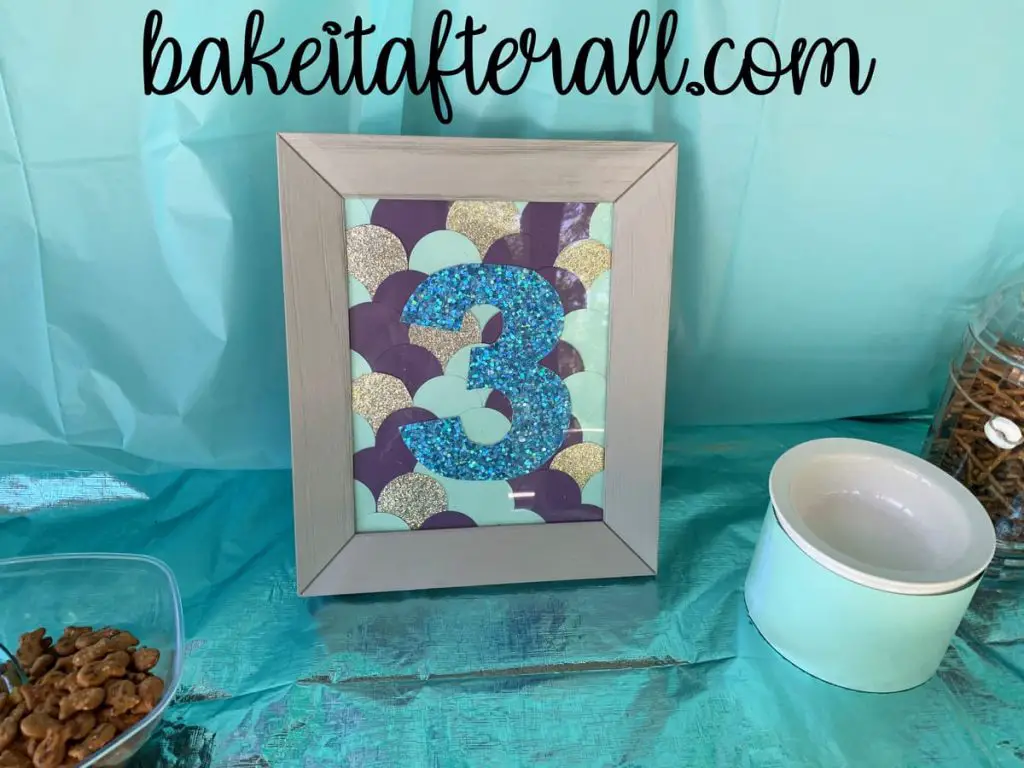 mermaid scales made with cardstock with a 3 on top inside a picture frame