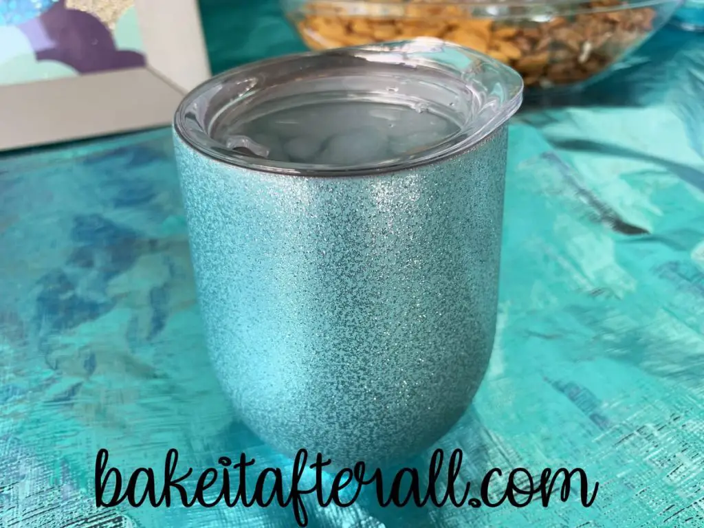sparkly blue wine tumbler on a table filled with ice water