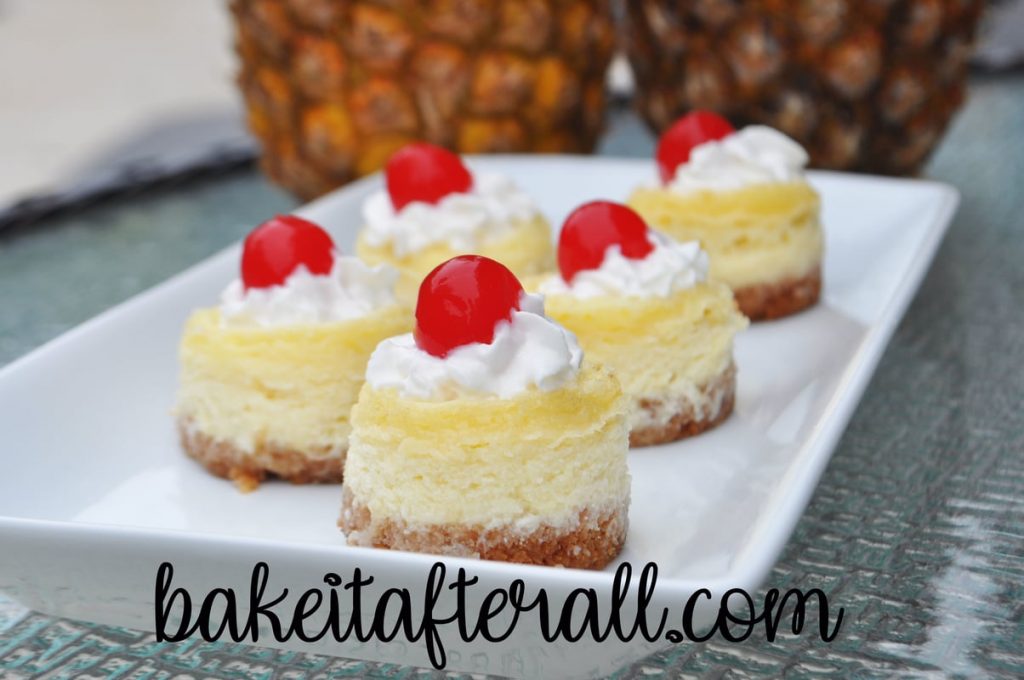 mini pina colada cheesecakes with whipped cream and maraschino cherries on top