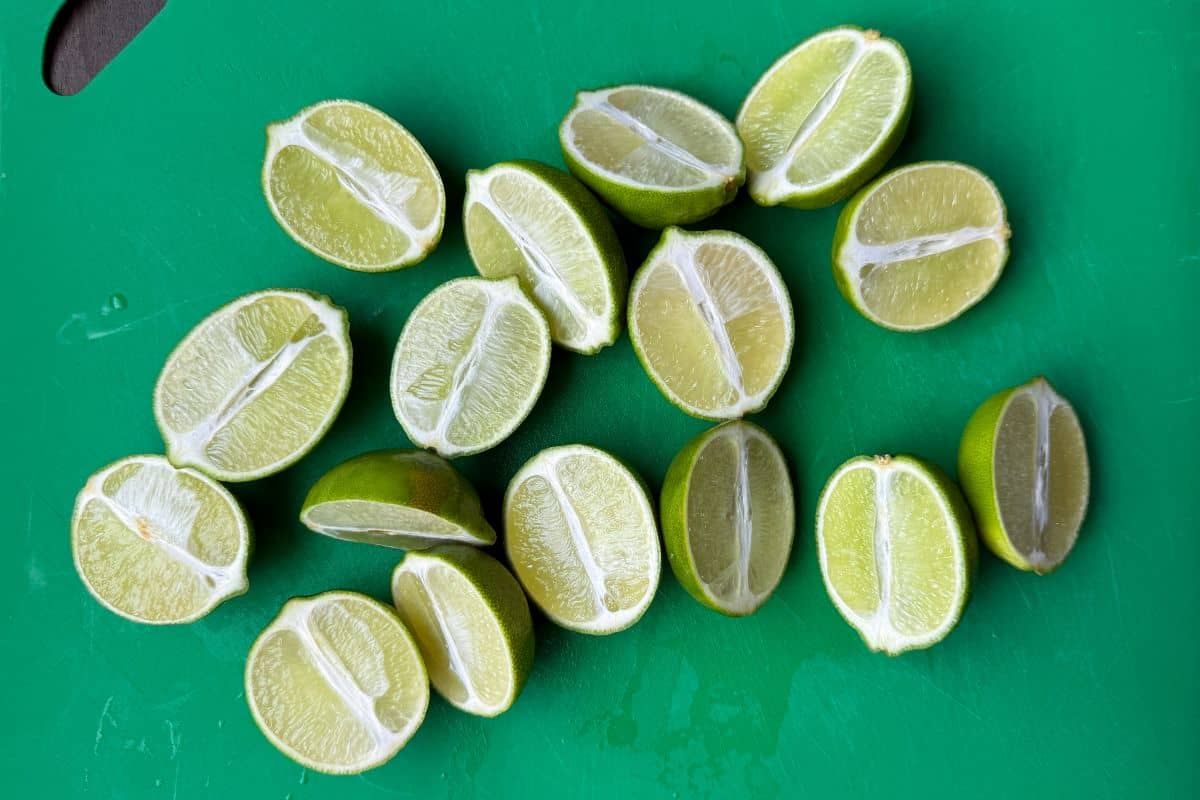 limes sliced in half on a cutting mat