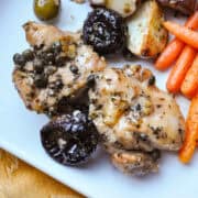 chicken marbella on a white plate with roasted carrots