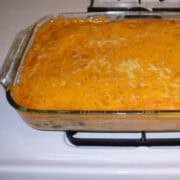 a glass casserole of fiesta chicken and spinach enchiladas on a stovetop