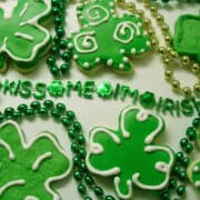 St. Patrick's Day Sugar Cookies with Royal Icing on a white surface with Mardi Gras beads around them