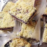 a stack of blueberry crumb bars with little squares of waxed paper between them