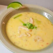 a bowl of chilli coconut chicken soup with a lime wedge on the side
