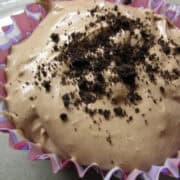 no bake chocolate cheesecake in a cupcake wrapper with crushed Oreo cookies on top