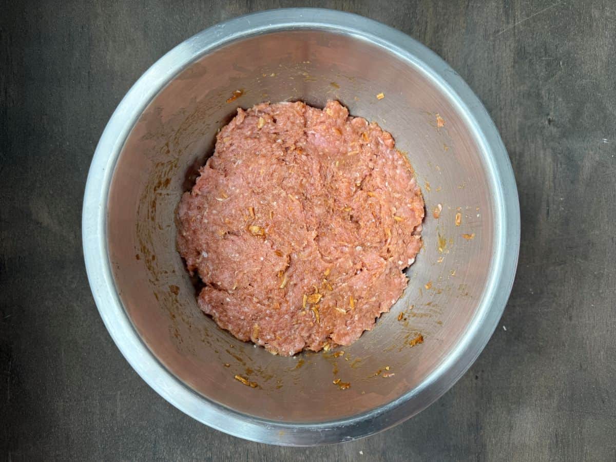 ground turkey mixed with seasoning in a large metal bowl