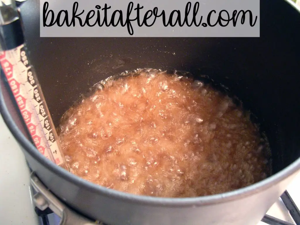 caramel cooking in a saucepan on the stove with a candy thermometer