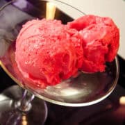 2 scoops of raspberry sorbet in a glass martini glass