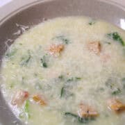 a bowl of chicken sausage florentine soup with Parmesan cheese on top