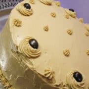 a chocolate fudge cake with coffee buttercream on top decorated with chocolate covered espresso beans