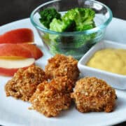 oven fried honey chicken nuggets on a plate with apple slices and broccoli