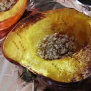 an acorn squash cut in half on a baking sheet filled with brown sugar and butter mixture