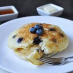 a plate of blueberry buttermilk pancakes with a bite on a fork