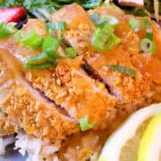 Lemon Chicken on a plate with salad, lemon slices, and a cut strawberry