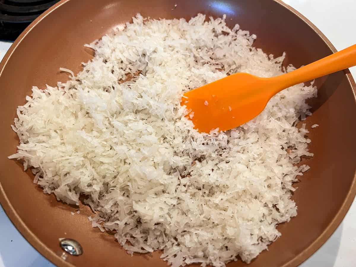 sweetened coconut in a saute pan with a small silicone spatula