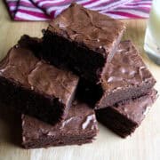 chewy fudgy brownies stacked up on a wooden surface