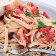 shrimp fra diavolo with linguine on a plate with a slice of Italian bread
