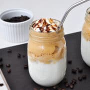 mason jars of easy dalgona whipped coffee with whipped cream and chocolate sauce and straws
