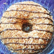 Samoa Bundt cake on a clear platter on a purple surface
