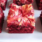 red velvet brownie with cheesecake swirl cut into squares on a white plate