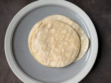 a plate with a stack of corn tortillas on top