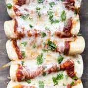 a glass casserole dish of chicken enchiladas with red chile sauce