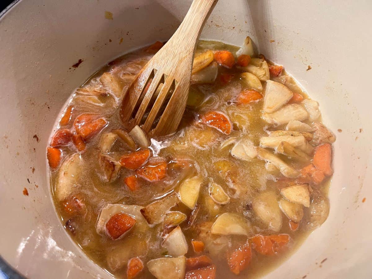chicken broth in a pan of root vegetables