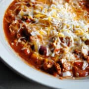 turkey chili in a bowl with cheese and onions on top