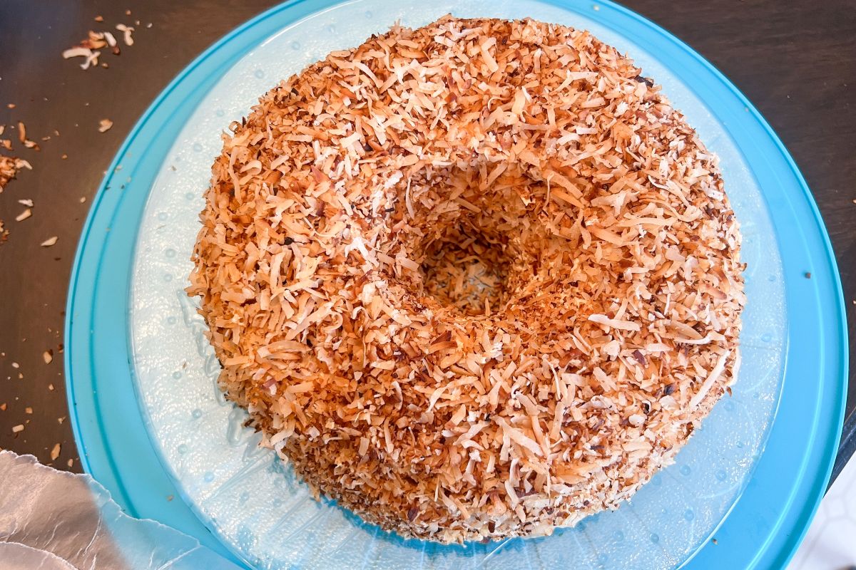 a Samoa Bundt Cake covered in toasted coconut before the chocolate stripes are added