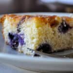 a square slice of blueberry boy bait on a plate with a fork