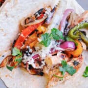 a grilled chicken fajita on a plate opened to show the toppings