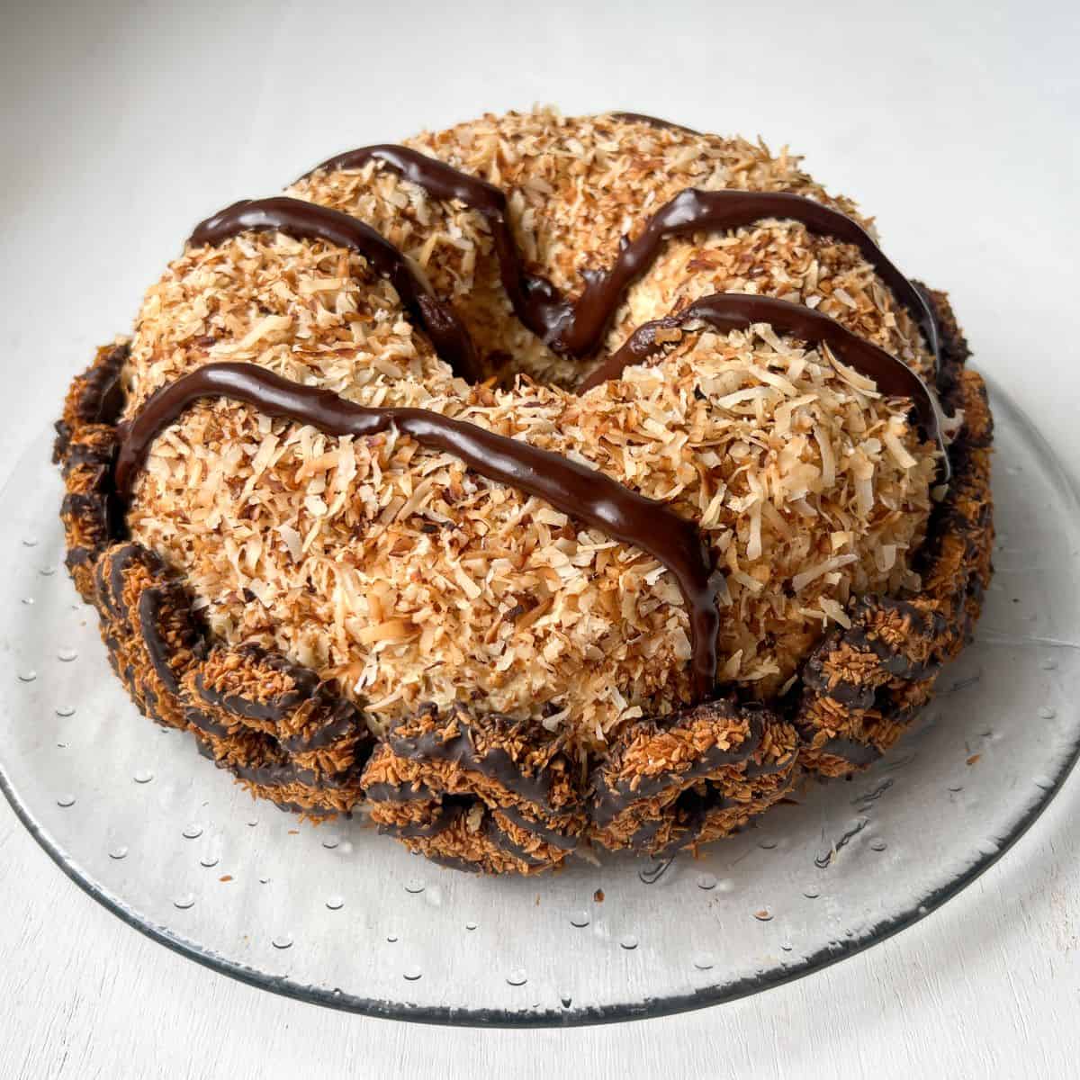 Samoa Bundt Cake with thick chocolate ganache lines piped on top and Samoa cookies lining the bottom edge