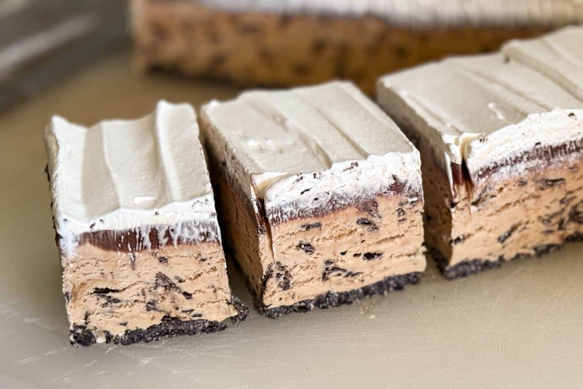an ice cream cake cut into squares on a cutting board