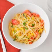 Summer Vegetable Pasta in a bowl on a white surface with a red napkin to the left