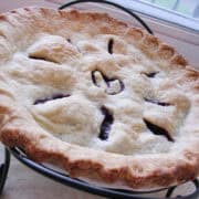 a sweet cherry pie in a pie plate on a pie plate stand