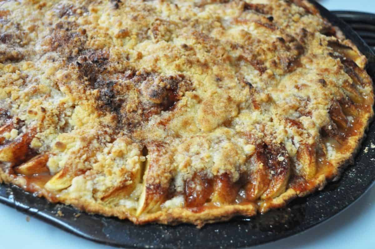 apple crumble pizza pie on a black pizza pan