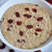 a bowl of steel cut oatmeal with dried cranberries scattered on top