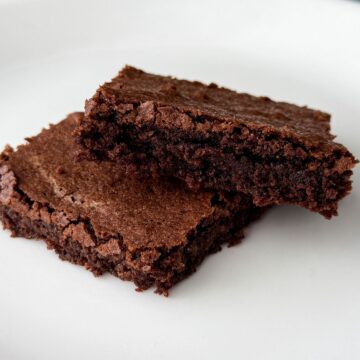 two dairy free soy free brownies stacked on a white plate