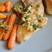 garlic braised chicken thighs on a plate with roasted carrots