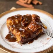 a slice of bread pudding on a plate topped with bourbon caramel sauce