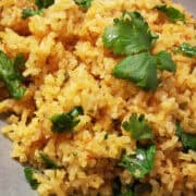 Mexican rice on a plate with fresh cilantro leaves on top