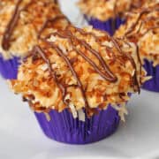 Samoa Cupcakes with purple foil liners on a white plate